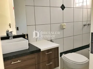Banheiro com pia e vaso sanitário em cerâmica branca.