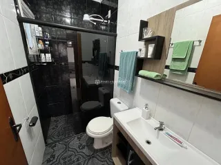 Foto de um banheiro com revestimento escuro e louças brancas.