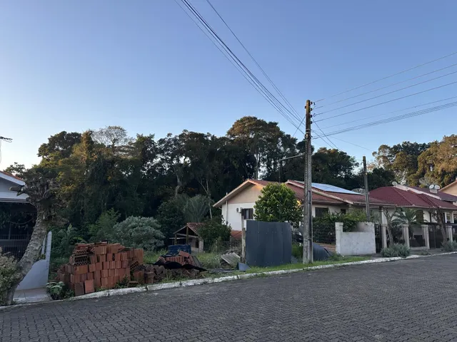 Foto da fachada de uma residência em Lajeado, Brasil, com vegetação e materiais de construção no primeiro plano.