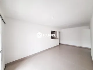 Ambiente interno de uma sala ampla com piso de porcelanato e paredes brancas.