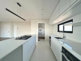 Cozinha moderna com armários brancos e piso claro.