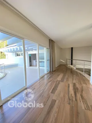 Vista interna de um ambiente com piso de madeira e portas de vidro.