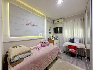 Quarto com cama e decoração em tons rosados.