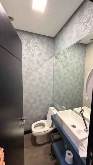 Foto de um banheiro com revestimento de papel de parede claro.