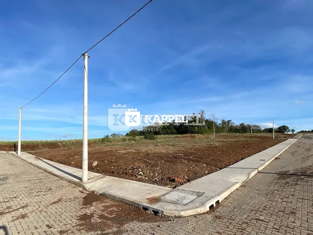 Vista externa de um terreno com estrada de terra e poste de luz sob um céu azul.