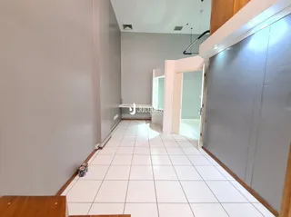 Corredor interno com piso de cerâmica branco.