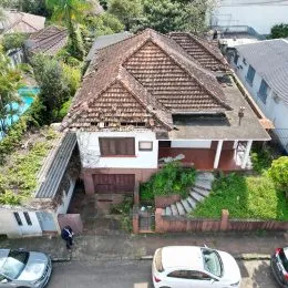 Fachada de uma casa residencial com telhado de telhas e vegetação ao redor.