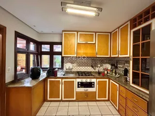 A cozinha apresenta armários de madeira e bancadas de pedra.