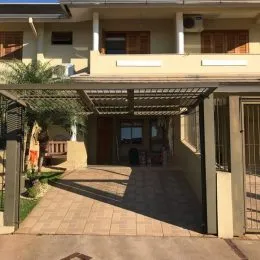 Vista de uma área externa coberta com estrutura de pergolado em uma residência.