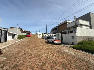Vista externa da residência com acesso por rua de paralelepípedos.