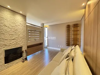 Sala de estar com piso de madeira e lareira em um imóvel em Lajeado.