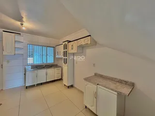 Foto de uma cozinha com armários brancos e piso claro.