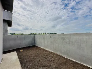 Parede externa de concreto com solo de cascalho.