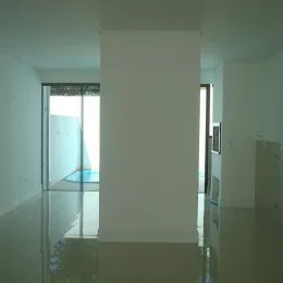 Foto de um espaço interno com paredes brancas e piso reflexivo.