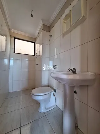 Banheiro com piso e paredes de cerâmica brancas.