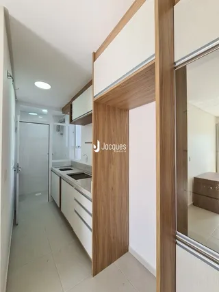 Corredor interno de uma residência com paredes brancas e piso claro.