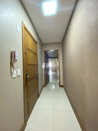 Corredor interno de uma residência com paredes claras e piso claro.