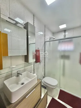 A foto mostra o interior de um banheiro com pia e box de vidro.