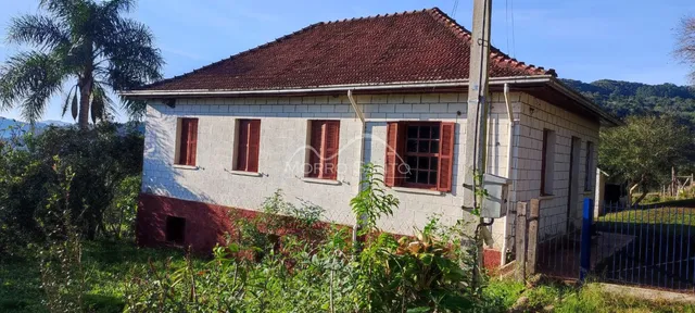 Foto da fachada de uma casa em Lajeado, Brasil, com telhado de telhas e vegetação no primeiro plano.