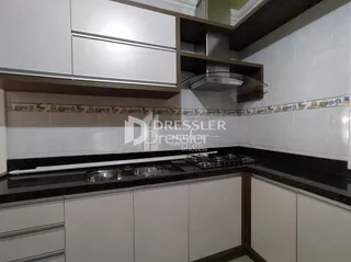 Uma cozinha com armários brancos e bancadas escuras.