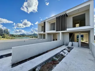Fachada moderna de uma casa em Lajeado, Brasil, com muro branco e paisagem ao fundo.