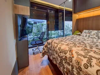 Quarto com cama grande e vista através de portas de vidro.