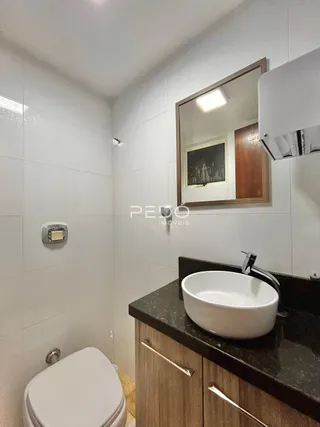 Foto de um banheiro interno com azulejos brancos e bancada escura.