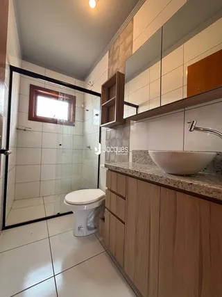 Foto de um banheiro com box de vidro e revestimento cerâmico.