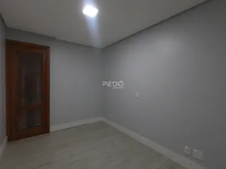Ambiente interno de uma sala com piso de madeira clara e paredes cinzas.