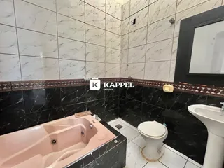 Banheiro com banheira e vaso sanitário em revestimento de azulejos e mármore.