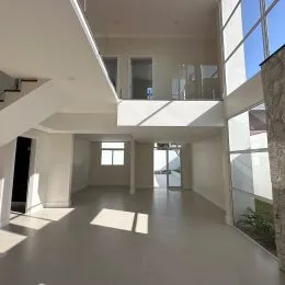 Interior de um ambiente com paredes brancas e grandes janelas.