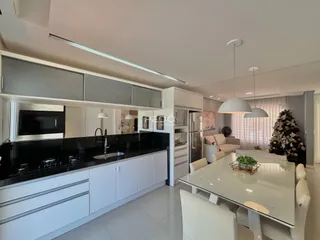 Interior de uma cozinha moderna com armários brancos e bancadas escuras.