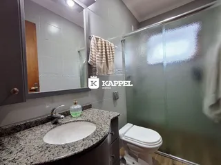 Banheiro com pia de granito e box de vidro na propriedade em Lajeado.