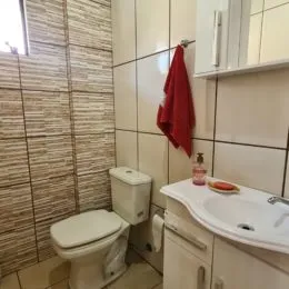 Foto de um banheiro com revestimento de azulejos brancos e vaso sanitário.