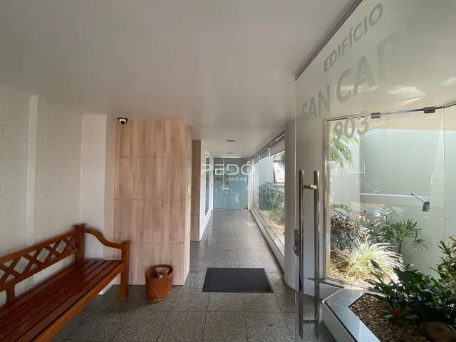 Hall de um corredor residencial com piso de cerâmica e móveis de madeira.
