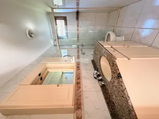 Foto de um banheiro com revestimento de cerâmica e divisória de vidro.