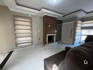 Sala de estar com parede de pedra e janelas amplas.
