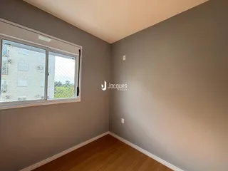 Quarto interno com parede cinza e piso de madeira clara.