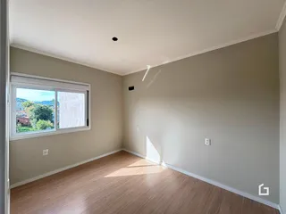 Sala de estar com piso de madeira clara e janela com vista para a natureza.