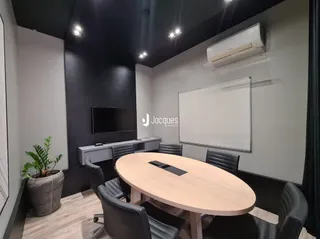 Sala de estar com mesa de madeira e televisão montada na parede.