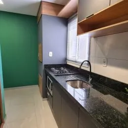 Foto de uma cozinha com armários escuros e bancadas pretas.