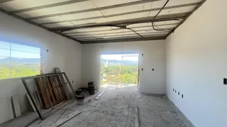 Interior de uma área em construção com paredes brancas e teto de concreto aparente.