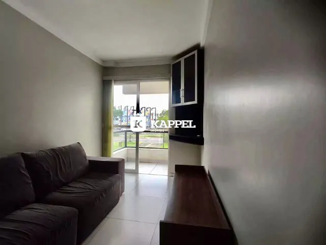 Sala de estar com sofá e porta de vidro que oferece uma vista externa.