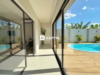 Vista da sala de estar com acesso a uma piscina externa e jardim.