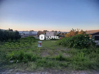 Vista externa de um terreno com vegetação alta e grama no primeiro plano.