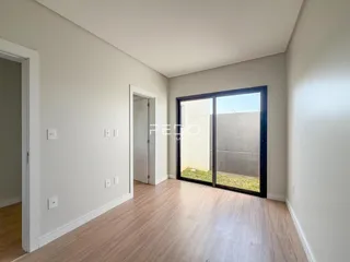 Ambiente interno com piso de madeira clara e grandes portas de vidro voltadas para o exterior.