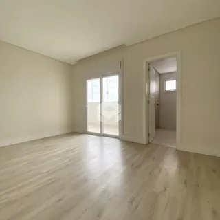 Ambiente interno de uma sala com piso de madeira clara e portas de vidro.