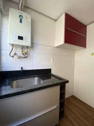 A cozinha apresenta bancada escura e revestimento branco nas paredes.