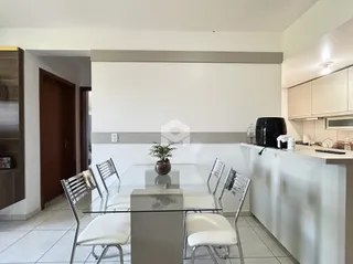 Uma sala de jantar com mesa de vidro e cadeiras em um apartamento.