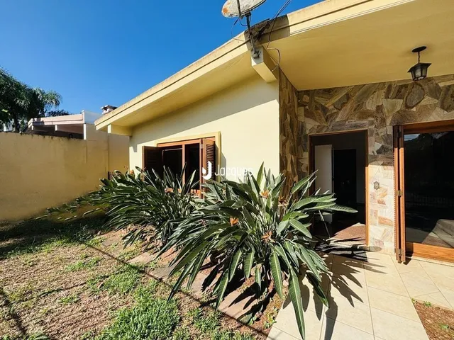Vista externa da propriedade com jardim e parede de pedra.